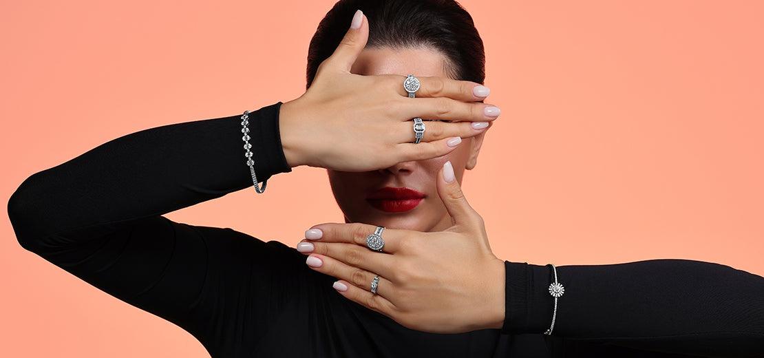 donna wearing Anello con diamantis e bracciali showcasing fine gioielli on hands against peach background