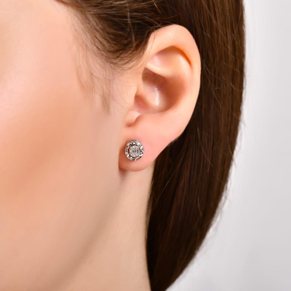 close-up of a woman's ear wearing a round diamond stud earring with halo setting